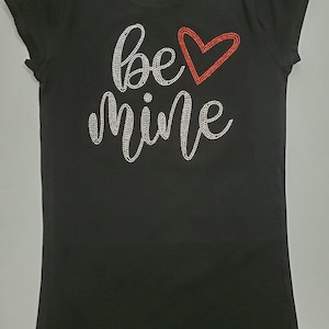 May include: Black t-shirt with the words "be mine" in silver rhinestones and a red rhinestone heart.