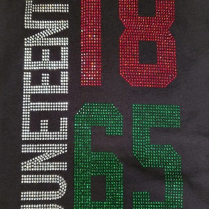 May include: A black t-shirt with the words "Forever 1865" in rhinestones. The numbers 18 are red, the number 6 is green, and the number 5 is green.