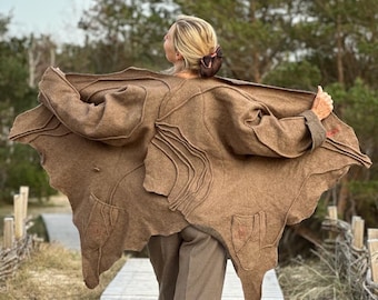 Peut inclure: Une veste en feutre marron avec un design unique présentant des formes et des lignes abstraites. La veste est ouverte et la personne qui la porte est dos à la caméra.