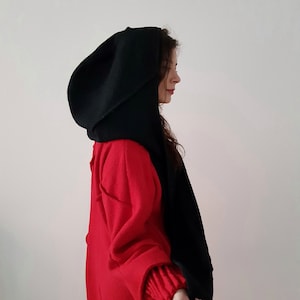 May include: A black hooded scarf with a long, flowing design. The scarf is made of a soft, warm material and is perfect for keeping warm in the winter.