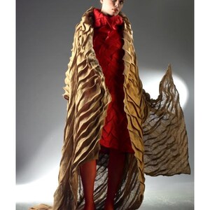 Peut inclure: Une femme portant un long manteau brun textur&eacute; et fluide sur une robe rouge. Le manteau a un design ondul&eacute; unique et la robe a un motif tiss&eacute;.