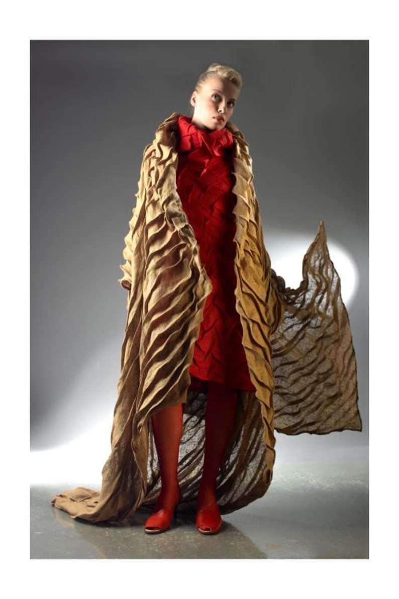 Peut inclure: Une femme portant un long manteau brun textur&eacute; et fluide sur une robe rouge. Le manteau a un design ondul&eacute; unique et la robe a un motif tiss&eacute;.