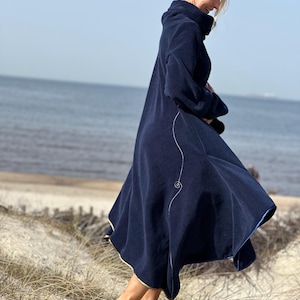 May include: A navy blue fleece coat with a long, flowing silhouette and a gold trim. The coat has a high collar and a decorative swirl design on the side.