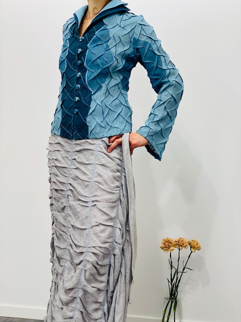 May include: A blue denim jacket with a textured, quilted design. The jacket has a collar, long sleeves, and a button closure.