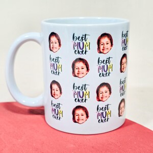 May include: White ceramic mug featuring a repeating pattern of a child's face and the text "Best Mum Ever" in purple, yellow, and pink. The mug has a curved handle and is suitable for hot or cold beverages.