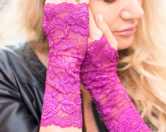 Könnte beinhalten: Ein Paar fingerlose Handschuhe aus fuchsiafarbener Spitze. Die Handschuhe sind aus zarter Spitze mit einem Blumenmuster.
