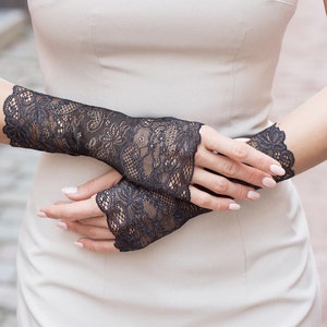 May include: A pair of black lace fingerless gloves with a delicate floral pattern.