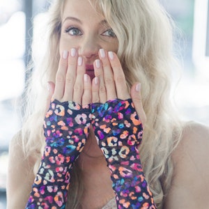 May include: A woman wearing a pair of black fingerless gloves with a colorful leopard print design. The gloves are made of a sheer, mesh fabric.