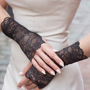 May include: A pair of black lace fingerless gloves with a delicate floral pattern.