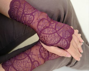 Könnte beinhalten: Ein Paar lange, burgunderfarbene Spitzenhandschuhe mit einem zarten Blumenmuster. Die Handschuhe sind durchsichtig und haben einen gewellten Rand.