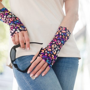 May include: A pair of fingerless gloves with a colorful leopard print design. The gloves are made of a sheer, stretchy fabric and are worn on both wrists.