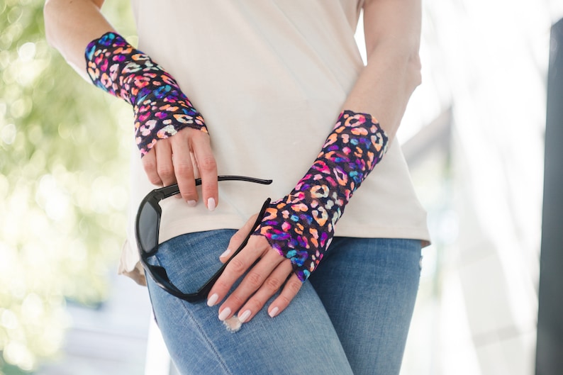 May include: A pair of fingerless gloves with a colorful leopard print design. The gloves are made of a sheer, stretchy fabric and are worn on both wrists.