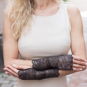 May include: A woman wearing a white sleeveless dress with black lace fingerless gloves.