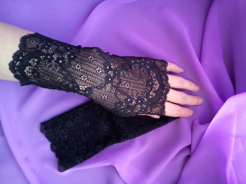 K&ouml;nnte beinhalten: Ein Paar schwarze fingerlose Handschuhe aus Spitze. Die Handschuhe sind aus zarter Spitze mit einem Blumenmuster.