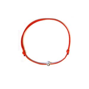 Könnte beinhalten: Ein rotes Armband mit einem kleinen silbernen Anhänger.