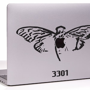May include: A silver laptop with a black sticker of a moth with an apple logo in the center. The number 3301 is printed on the bottom right corner of the laptop.