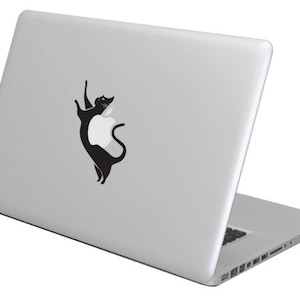 Puede incluir: Un portátil plateado con una pegatina de un gato negro en la tapa. El gato está colocado para que parezca que está sosteniendo el logotipo de Apple.