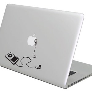 Può includere: Un computer portatile argentato con un adesivo in bianco e nero di un iPod, cuffie e il logo Apple sul retro.