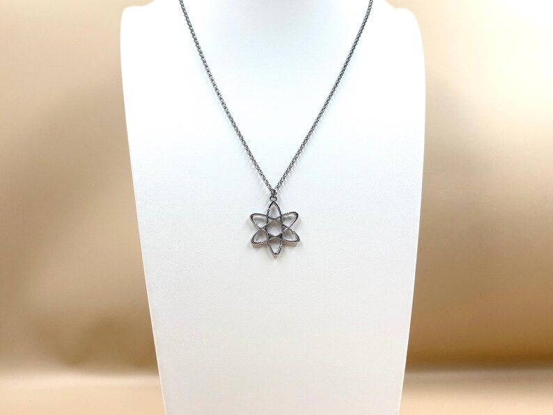 K&ouml;nnte beinhalten: Silberfarbene Halskette mit einem filigranen, sechszackigen Blumenanh&auml;nger. Der Anh&auml;nger h&auml;ngt an einer feinen Kette. Die Halskette wird auf einer wei&szlig;en B&uuml;ste vor neutralem Hintergrund pr&auml;sentiert.