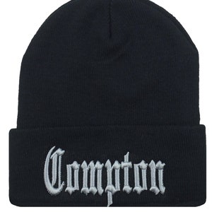 May include: A black knit beanie with a silver embroidered word "Compton" on the cuff.