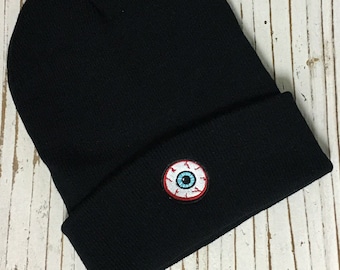 May include: Black beanie with a red and white eyeball embroidered on the front.