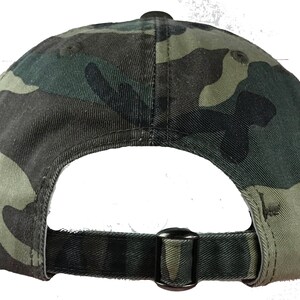 May include: A camouflage baseball cap with a black adjustable strap and buckle. The cap is made of a soft, cotton fabric.