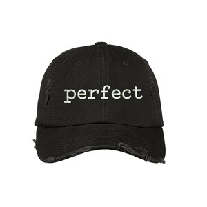 May include: Black distressed baseball cap with the word "perfect" embroidered in white on the front.