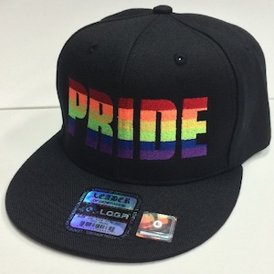 May include: Black baseball cap with a rainbow embroidered "PRIDE" on the front. The cap has a curved brim and a snap closure.