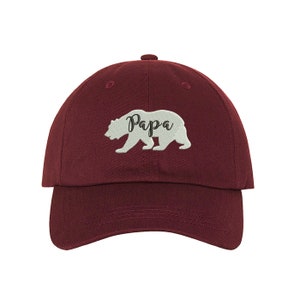 May include: A maroon baseball cap with a white embroidered bear and the word "Papa" on the front.
