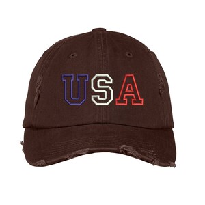 May include: A brown distressed baseball cap with the word "USA" embroidered in blue, white, and red.