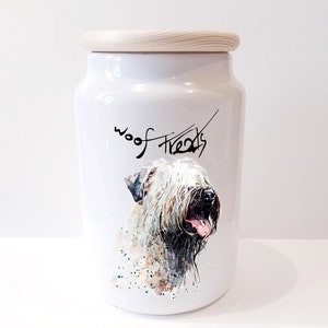 Puede incluir: Tarro de cerámica blanca para golosinas para perros con tapa de madera. El tarro tiene una ilustración de acuarela de un Soft Coated Wheaten Terrier y el texto "woof treats".