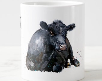 Puede incluir: Una taza de cerámica blanca con una ilustración de acuarela en blanco y negro de una vaca. La vaca está tumbada y mirando al espectador. El fondo es blanco con algunos pequeños puntos azules y rojos.