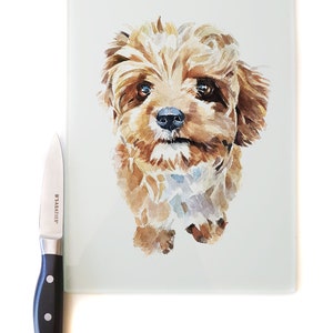 May include: A watercolor painting of a brown and white dog on a white glass cutting board. The dog is looking directly at the camera with its tongue slightly sticking out.