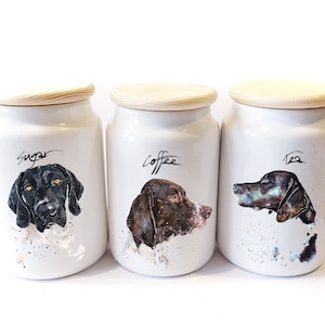 May include: Three white ceramic canisters with wooden lids. Each canister features a different dog breed illustration and the words "Sugar", "Coffee", and "Tea" written in black.