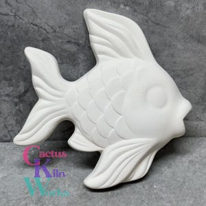 May include: White ceramic fish figurine with a detailed design of scales and fins. The fish has a large, round eye and a slightly open mouth.