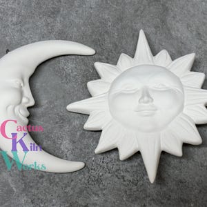 May include: White ceramic wall decor set featuring a crescent moon and a sun with a face. Both pieces have a 3D design.