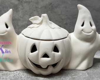 May include: White ceramic Halloween decoration featuring two ghosts flanking a pumpkin with a lid. The pumpkin has a carved jack-o'-lantern face.