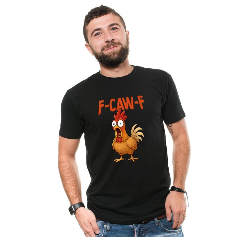 May include: Black t-shirt with the text "F-CAW-F" in orange letters above a cartoon chicken with a surprised expression. The chicken is brown, yellow, and red. The t-shirt is short-sleeved.
