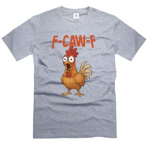 May include: A light gray t-shirt featuring a cartoon chicken with an open beak and wide eyes. Above the chicken is the text "F-CAW-F" in orange letters. The chicken is brown, red, and yellow.