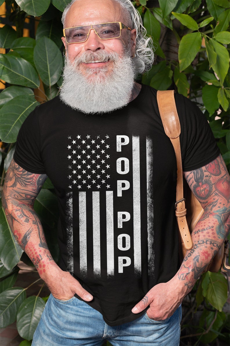 May include: A black t-shirt with a white distressed American flag design. The word "POP" is written vertically down the flag.