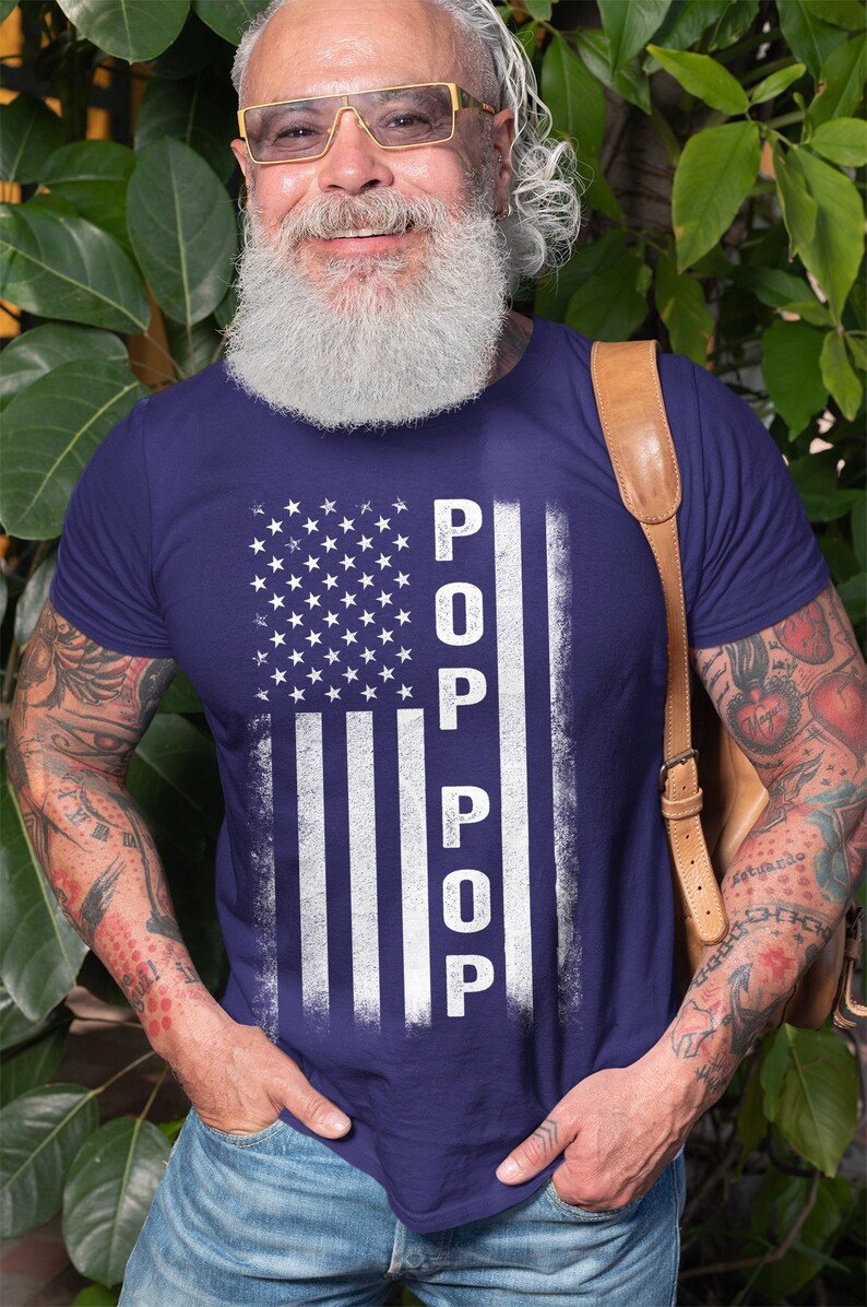 May include: A navy blue t-shirt with a white distressed American flag design and the word "POP" vertically down the right side of the flag.