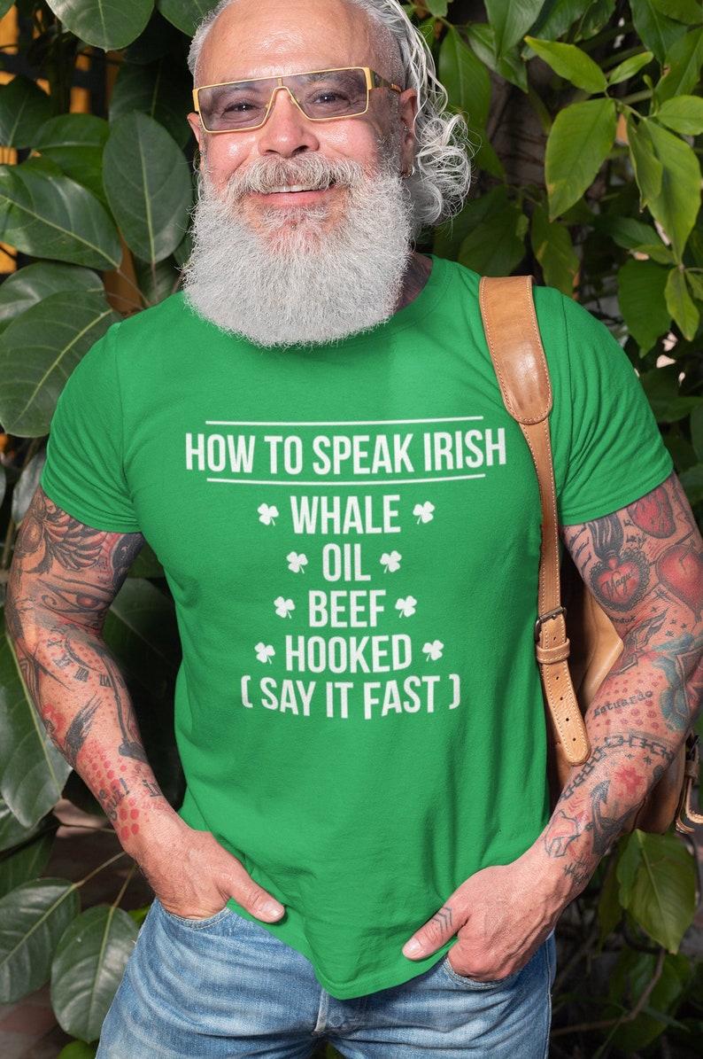 May include: A man wearing a green t-shirt with the text "HOW TO SPEAK IRISH *WHALE* *OIL* *BEEF* *HOOKED* (SAY IT FAST)" printed on it.
