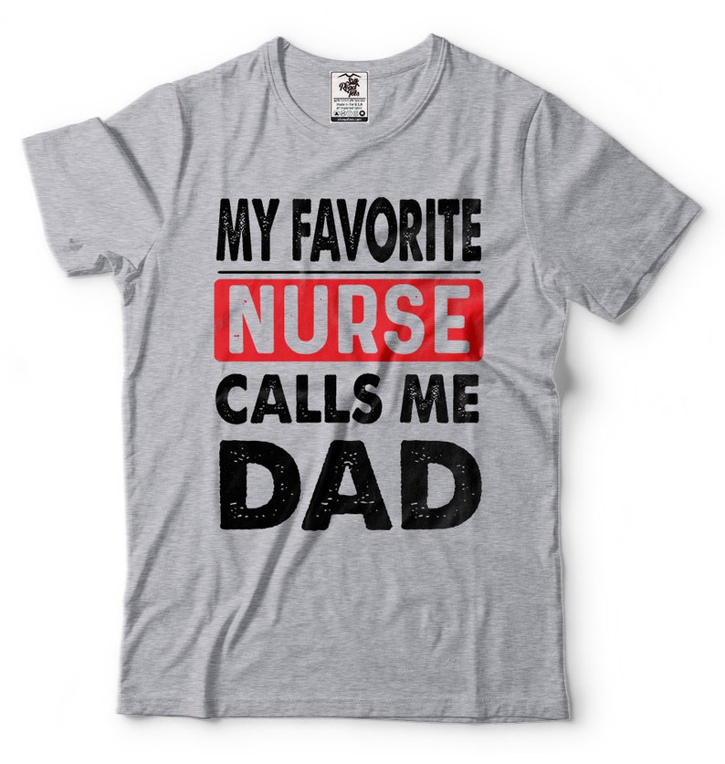 May include: Gray t-shirt with the text "My Favorite Nurse Calls Me Dad" in black and red lettering. The word "Nurse" is in a red rectangle.