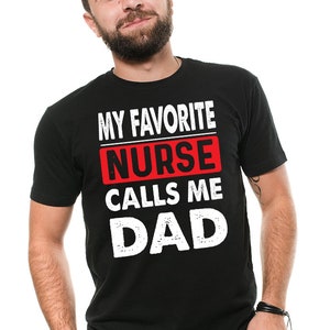 May include: Black t-shirt with white text that reads "My Favorite Nurse Calls Me Dad". The word "Nurse" is in a red box.
