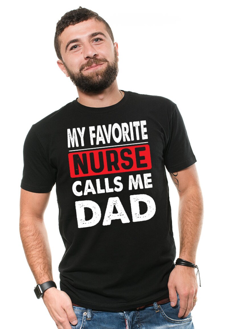 May include: Black t-shirt with white text that reads "My Favorite Nurse Calls Me Dad". The word "Nurse" is in a red box.