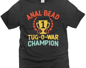 May include: Black t-shirt with the text "ANAL BEAD TUG-O-WAR CHAMPION" in a colorful design. The design includes a gold trophy with the number "1" and a beaded chain.
