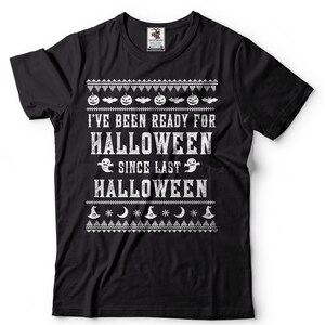 May include: Black t-shirt with a white graphic print that says "I've been ready for Halloween since last Halloween". The graphic includes pumpkins, bats, ghosts, and witch hats.
