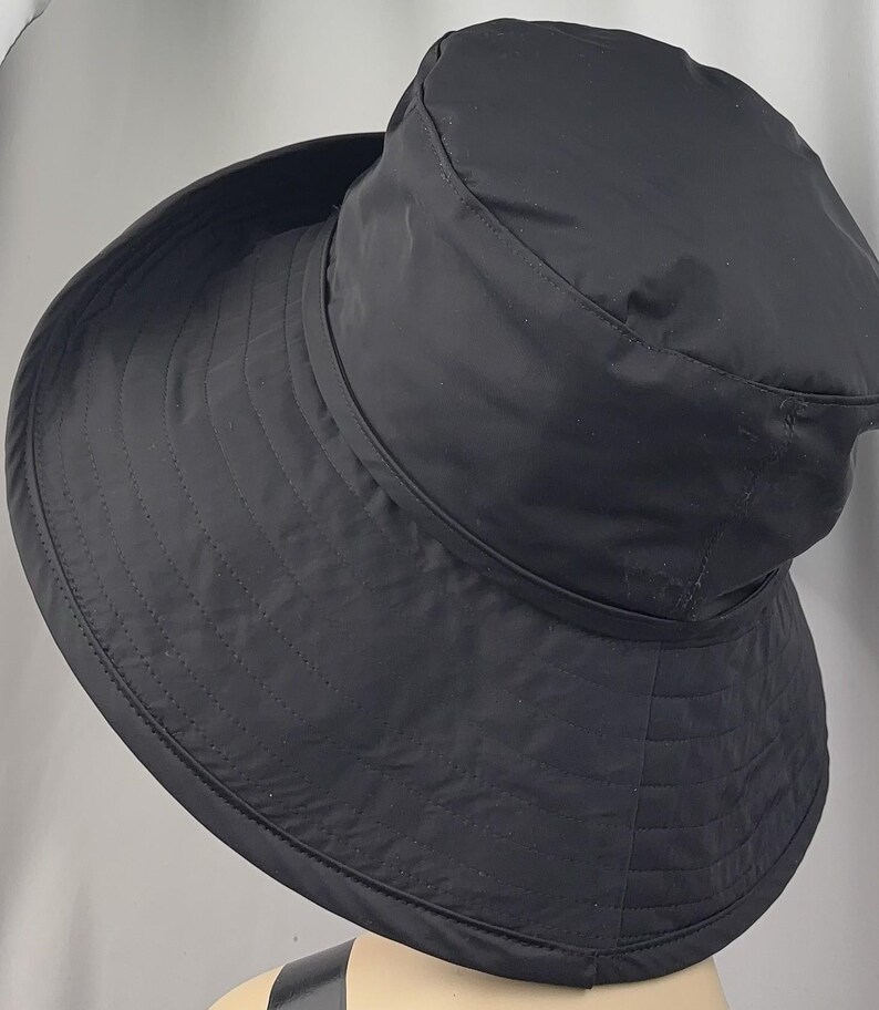 Pu&ograve; includere: Un cappello nero a tesa larga con un motivo trapuntato. Il cappello presenta una corona arrotondata e un'ampia tesa rivolta verso il basso. Il cappello &egrave; realizzato in un materiale liscio, possibilmente resistente all'acqua, ed &egrave; progettato per la protezione solare.