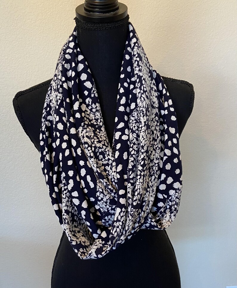 May include: A black and white infinity scarf with a floral and polka dot pattern.