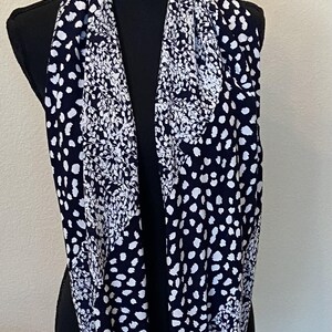 May include: A black and white infinity scarf with a floral and polka dot pattern.